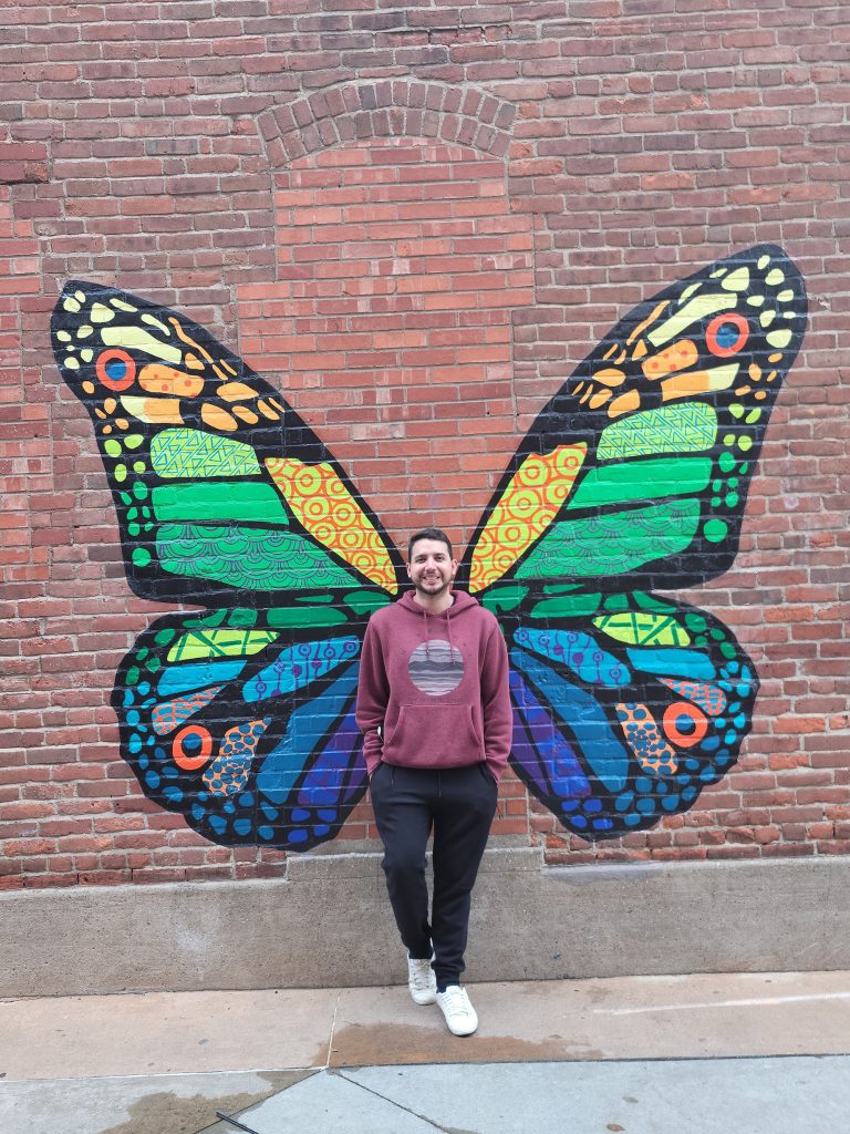 Person in front of brick wall with painted butterfly wings